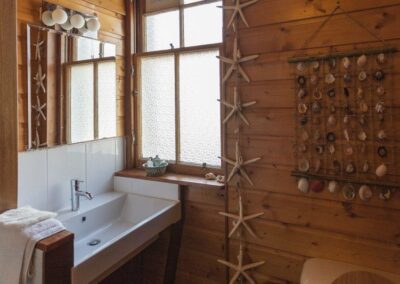 White sink next to window. Wooden walls with starfish and shells as decoration