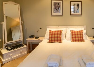 Double bed with bedside tables. On the left is a swivelable mirror