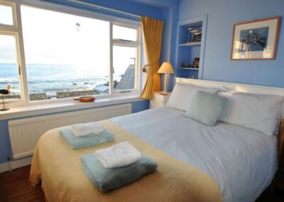 Double bed with towels at the foot. A large window looks out to the sea.
