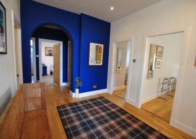 Wooden floors with a tartan rug, a wooden pew, blue and white walls