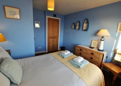 Blue walls in the bedroom. On the wall are three small boats.