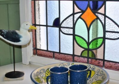 Ornament of a seagull on a window sill in front of a stained glass window