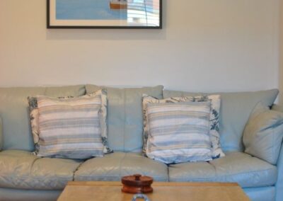 Painting of boat and piers hanging on the wall above sofa