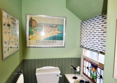 Toilet beneath a framed poster of St Andrews castle.