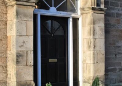 Black front door, framed in white with arched window above.