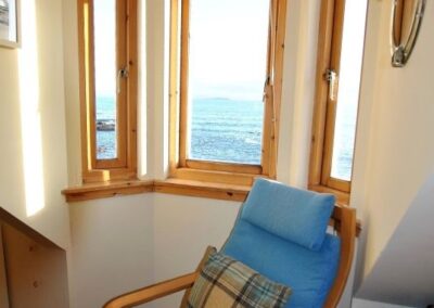Views of the sea to the left of a blue chair and footstool