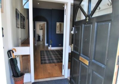 Open door into small vestibule with pot of umbrellas. Spacious hallway beyond.