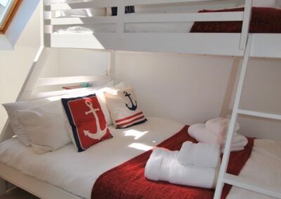 White framed triple-sleeper bunk with double beneath and single above. White linen with red features.