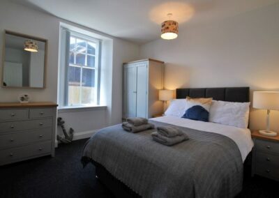 Double bed with bedside tables and lamps either side. Between the bed and the window on the left is a wardrobe.