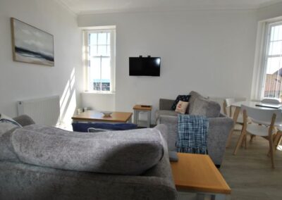 View from behind a grey sofa towards the lounge on the left and dining area on the right