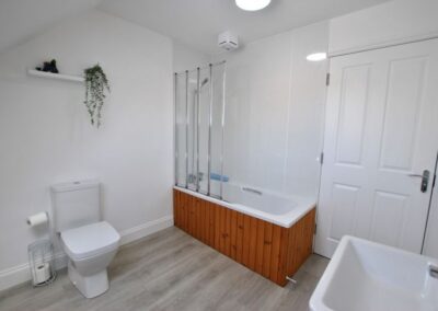 White suite with shower over bath and transparent shower screen.