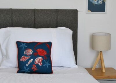 Bed with sea life design cushion, towel and lamp next to the bed.