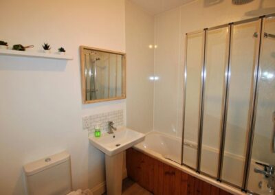 White bathroom suite with shower screen and shower over the bath