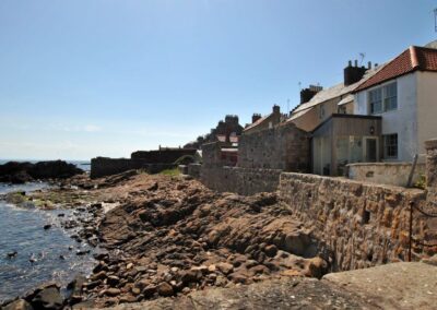 Houses behind a sea wall looking over rocks and down to the sea