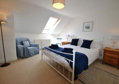 Double bed with white and navy linen beneath a sloped ceiling