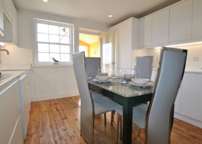 White kitchen cabinets, wooden floor and table in the middle set for four.