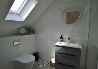 Lavatory and sink beneath a sloped roof, illuminated by a Velux window in the roof.
