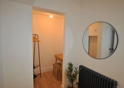 Mirror on wall to right of dressing area with hangers and dressing table.