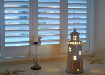 Sea-themed ornaments: a curlew and an illuminated lighthouse between two starfish.