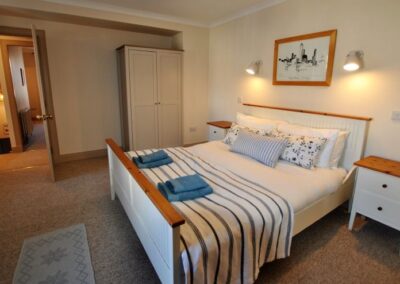 Double bed in centre of room. On the far side of the bed is a door to the corridor and a wardrobe.