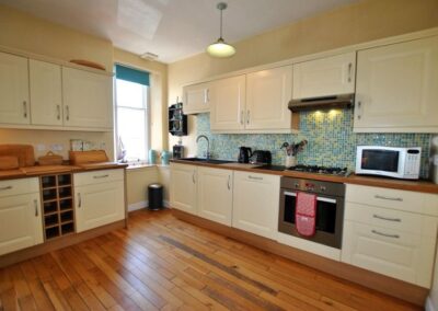 Spacious kitchen with cream-coloured wooden cabinets. There is a window in the corner next to the sink.