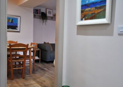 To the right of the doorway to the dining area hangs a bright painting of a scene overlooking fields and the sea.