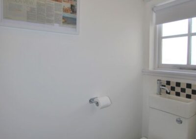 White lavatory on a black and white checked floor, with a window behind.