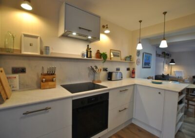 L-shaped kitchen counters with oven and hob beneath an extractor unit.