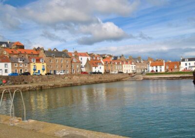 View across Cellardyke harbour towards traditional cottages and townhouses, most with red tiled roofs.