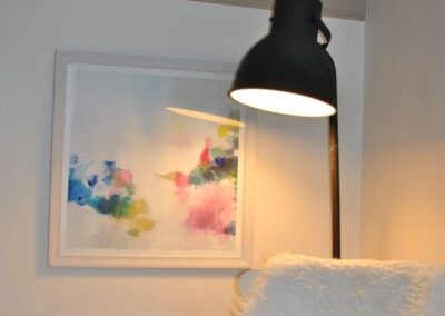 Lamp over white wooden rocking chair draped in a faux sheepskin.