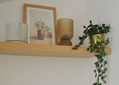 Close up of shelf with a plant, picture and vase