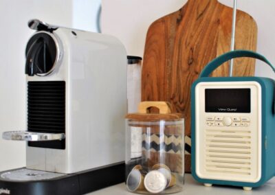 Radio next to coffee machine, chopping board and a jar of coffee pods.
