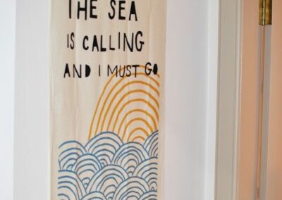 Wall-mounted banner reads: The sea is calling and I must go.
