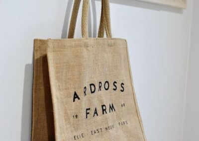 Hessian bag from a local farm shop hanging on a wall-mounted, wooden coat rack.