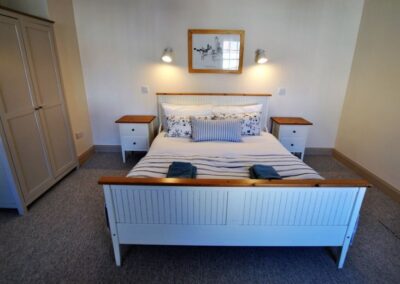 Double bed between bedside tables. A wardrobe sits to the left of the bed.