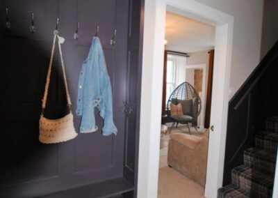 Shoe storage beneath coat hooks to the left of the door through to the lounge and to the right of that stairs leading up.