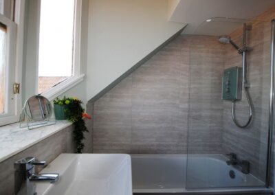 Shower over bath. There is a narrow portion of sloping roof over the foot of the bath.