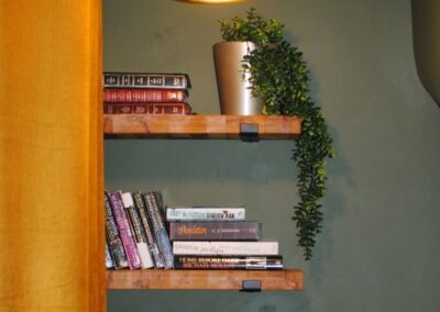 Gold-coloured lamp over three shelves of books.