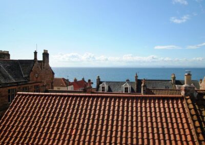 View across red tiled roofs to the sea beyond.
