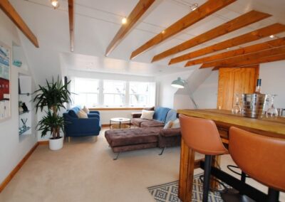 White room with windows at end and exposed wooden beams.