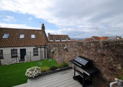 View of sea over garden wall and between rooftops.