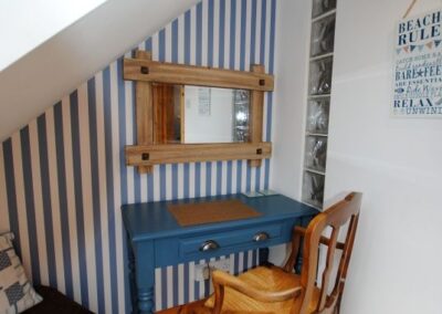 Blue desk and chair beneath stairs.