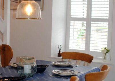 Table set with plates and cutlery beneath a hanging glass lamp.