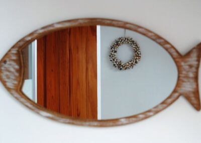 Reflection of circular wall hanging in fish-shaped mirror.