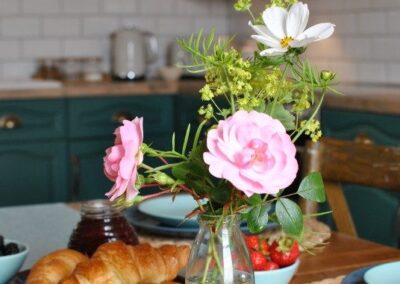 Close-up of croissants, strawberries and a bottle of summer flowers.