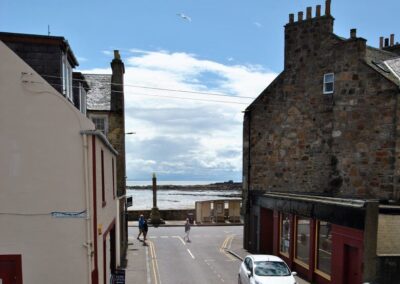 View down street towards the old market cross and the sea beyond. On the right is an Indian restaurant.