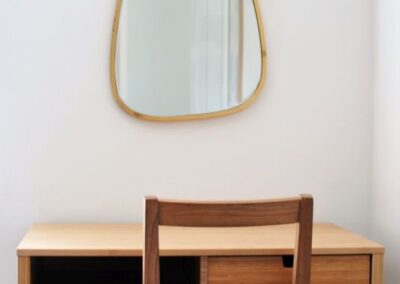 Wooden dressing table with one drawer beneath a a wall-mounted mirror.