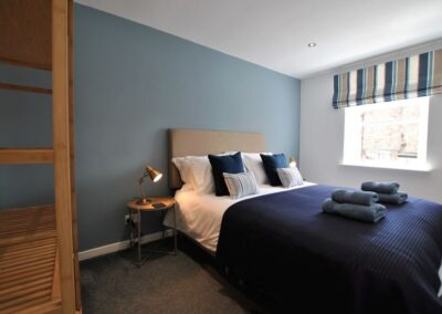 Blue feature wall behind bed. Deep blue and gold colours on bed and window blind.