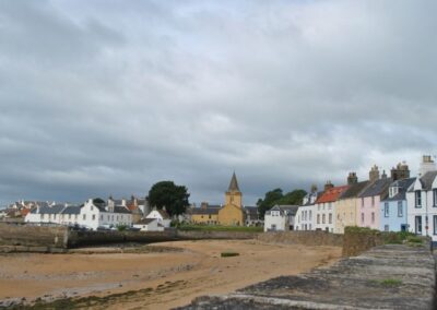 View along beach past colourful homes towards an old church building.