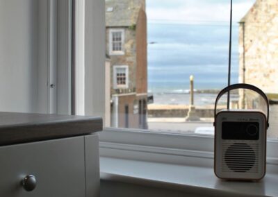 Focus on radio on kitchen windowsill. In the background, out of focus, the sea.